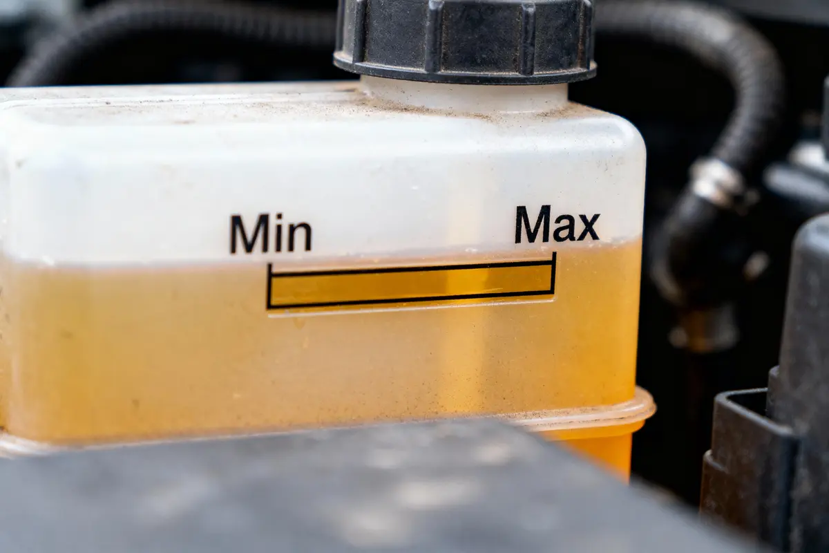 Récipient de liquide de voiture avec niveaux Min et Max visible, liquide présent juste en dessous de Max.