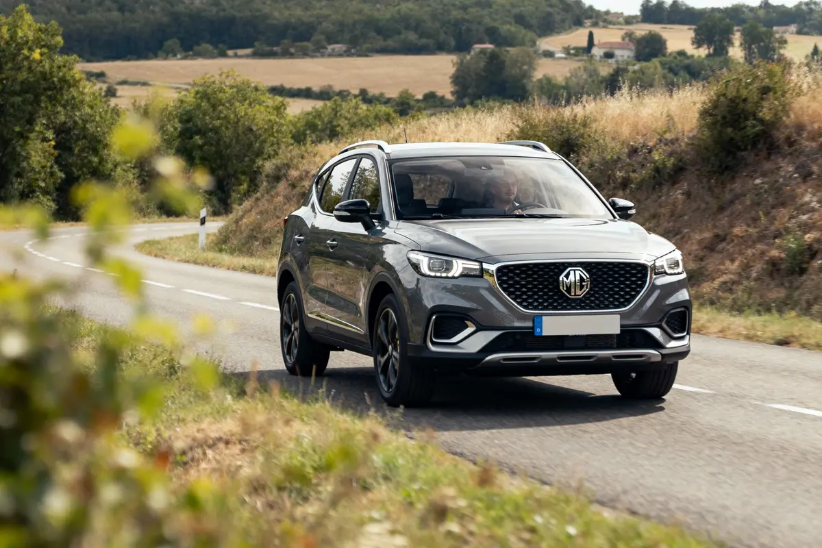 SUV gris sur une route de campagne sinueuse, paysage rural verdoyant en arrière-plan.