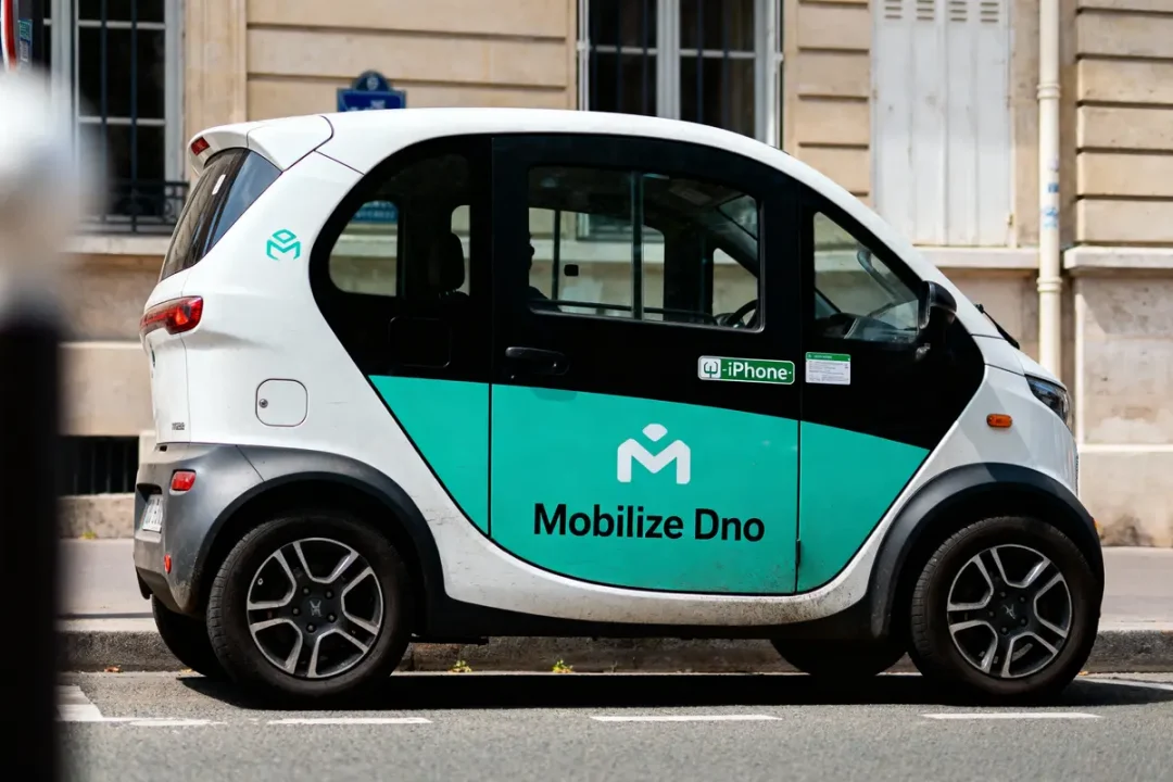 Petite voiture électrique "Mobilize Dno" blanche et verte stationnée devant un bâtiment.