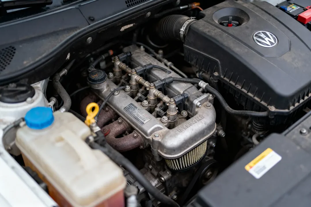 Moteur de voiture sous capot ouvert avec logo Volkswagen visible, câbles et composants mécaniques exposés.