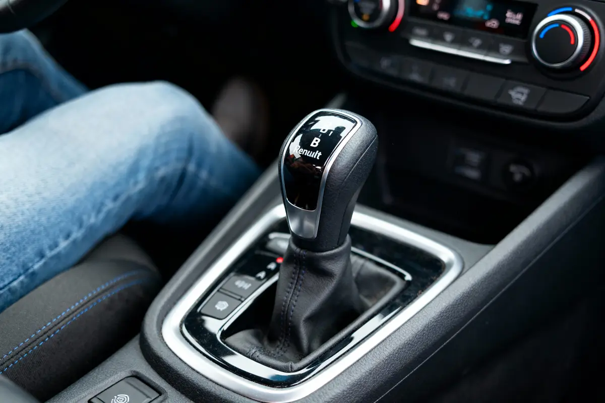 Levier de vitesse automatique d'une voiture Renault, intérieur moderne, détails chromés, cadran de climatisation visible.