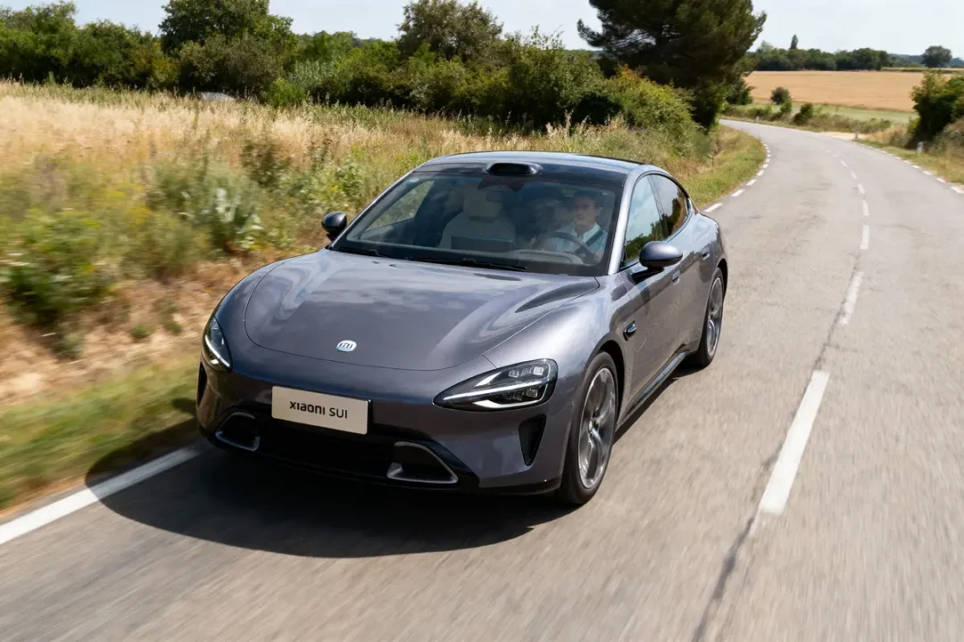 Voiture Xiaomi SUI grise sur route campagne, conduite par homme, arbres environnants.