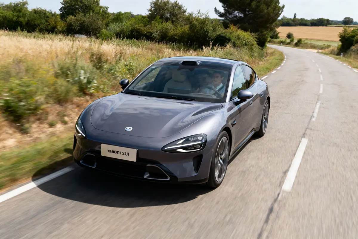 Voiture Xiaomi SUI grise sur route campagne, conduite par homme, arbres environnants.