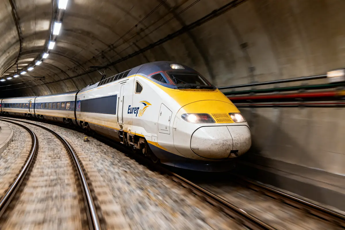 Train à grande vitesse Eurostar traversant un tunnel courbé, éclairé par des lumières au plafond.