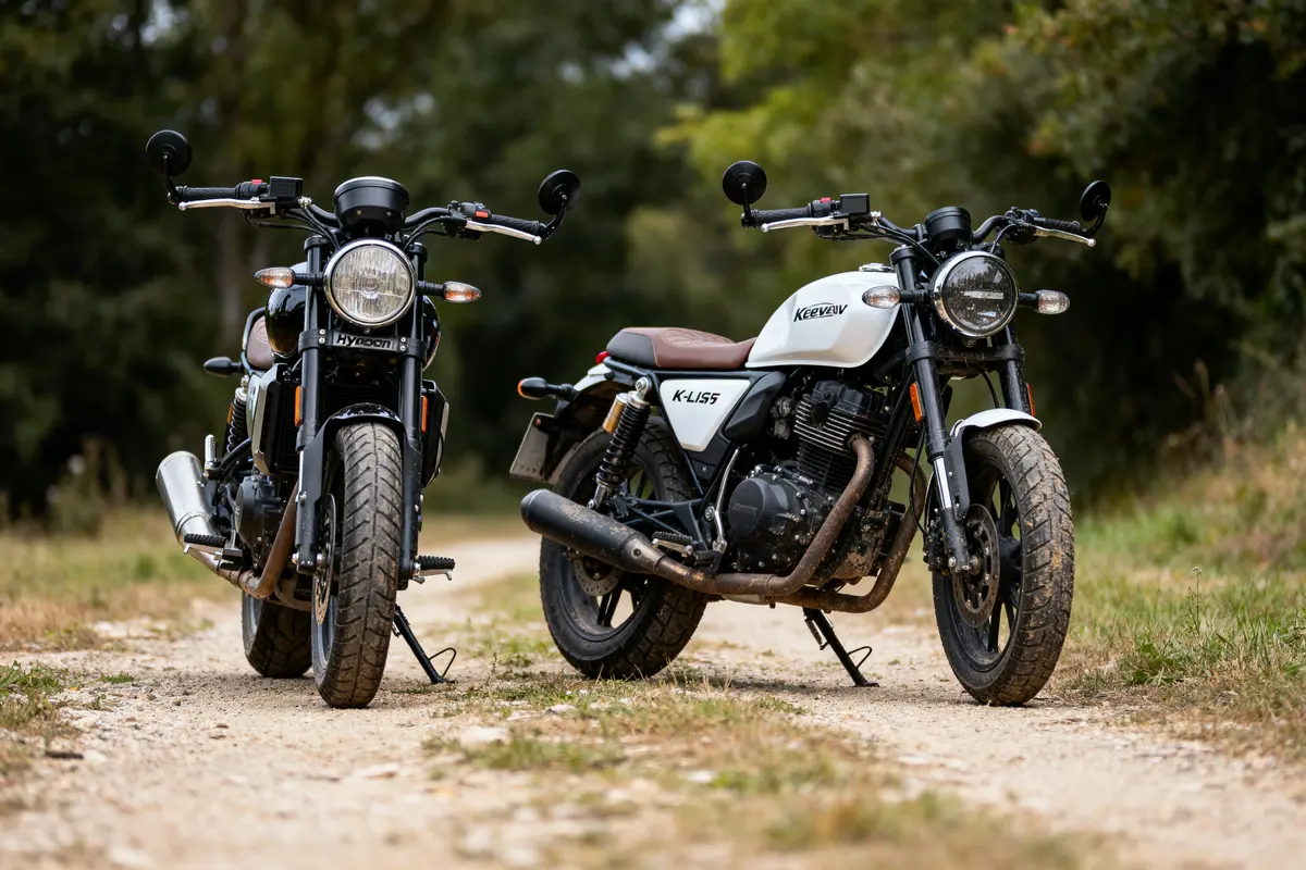 Deux motos stationnées sur un chemin de terre, entourées de verdure.