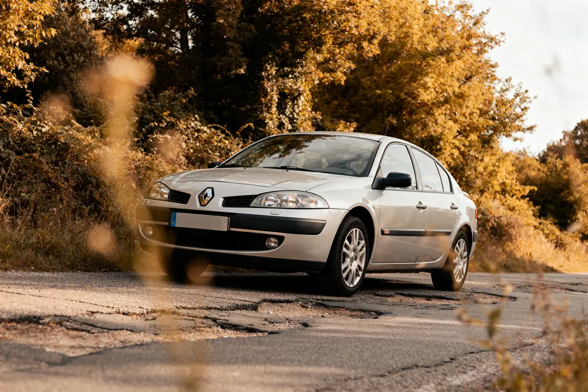 Renault Laguna cars roulant sur route forestière avec feuillage automnal en arrière-plan