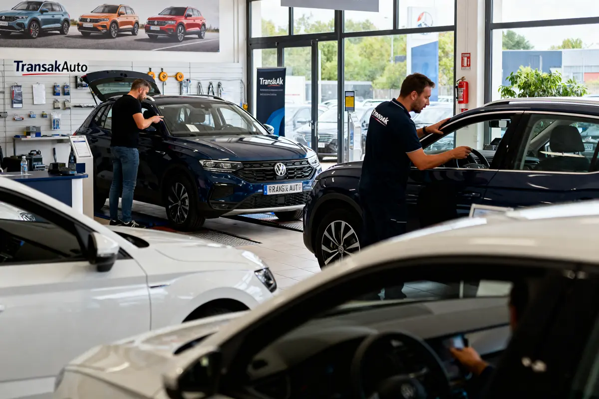 Atelier automobile avec mécaniciens travaillant sur voitures Volkswagen dans garage lumineux. Affiches de voitures colorées visibles.