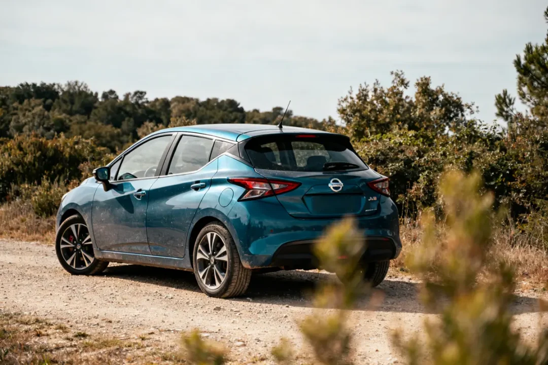Nissan Micra bleu garée sur chemin de terre entouré de végétation verdoyante