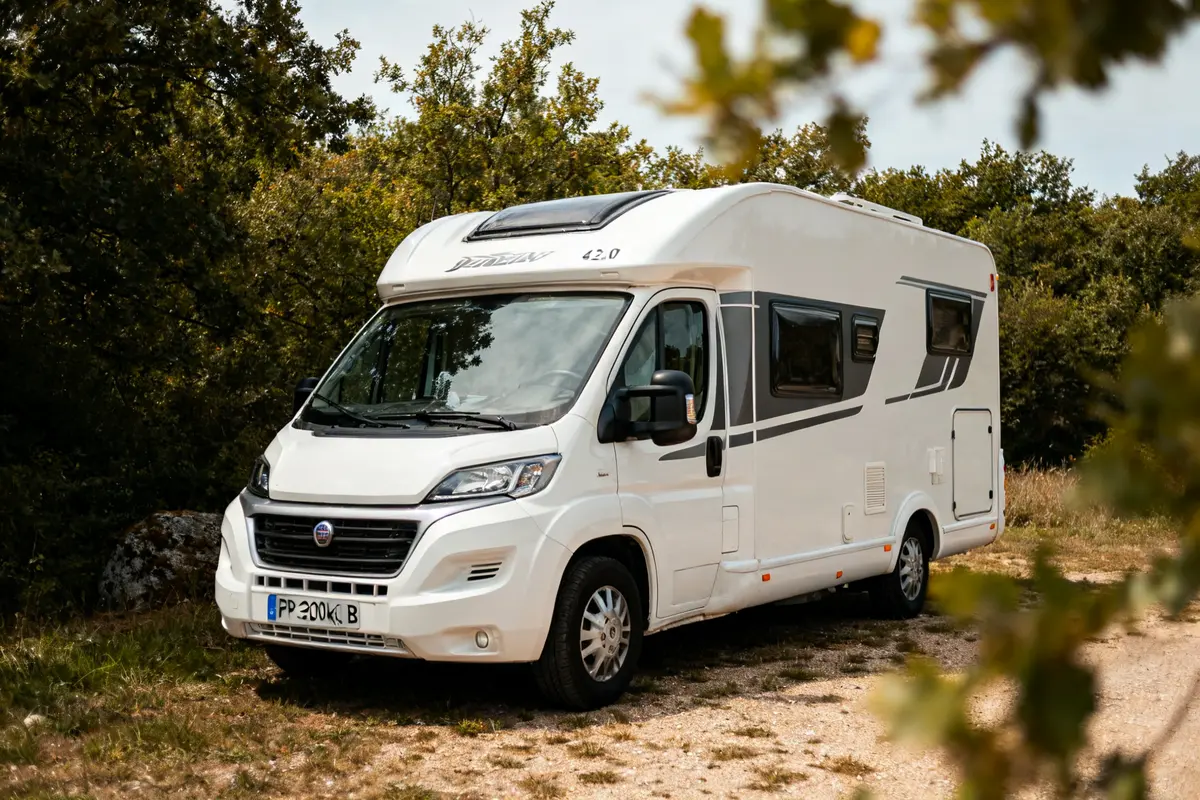 Camping-car permis B 4250 kg stationné dans une clairiÚre entourée de végétation
