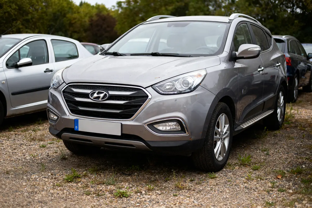 SUV gris Hyundai X35 occasion garé sur un parking extérieur en gravier