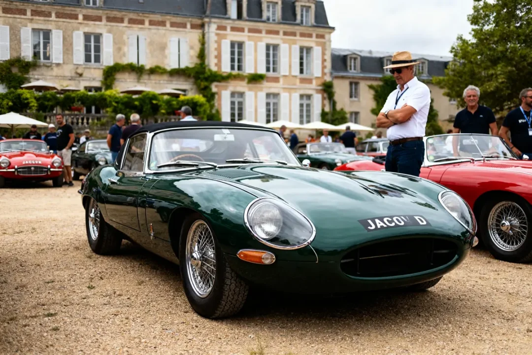 Voiture de collection : ancien Jaguar vert exposé devant une demeure historique avec visiteurs