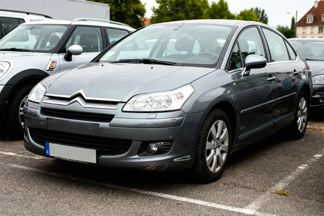 Voiture Citroën C4 grise garée sur un parking extérieur avec d'autres véhicules autour