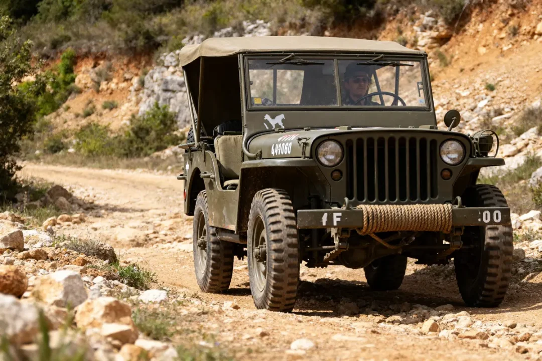 Jeep militaire roulant sur un chemin rocailleux en pleine nature avec un conducteur vigilant