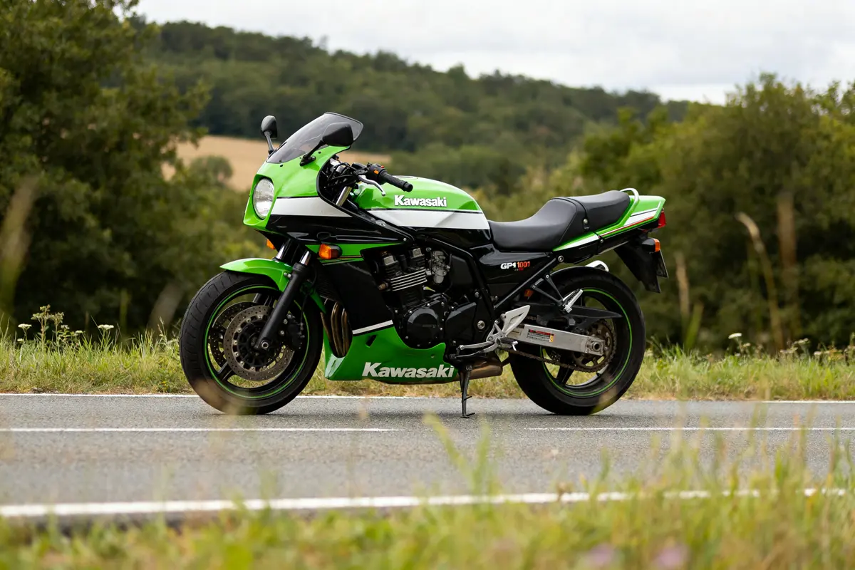 Moto Kawasaki GPZ 1000 RX verte stationnée sur une route de campagne.