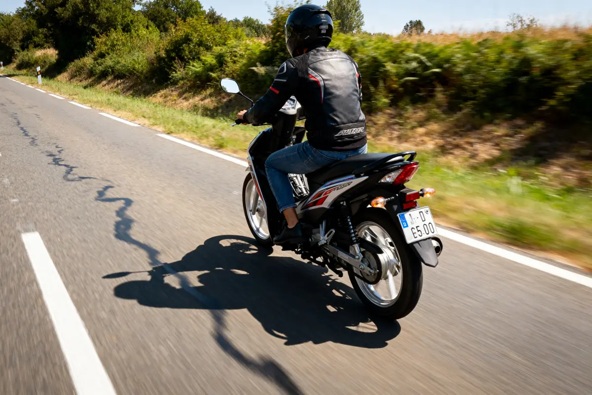 Motard sur route avec la moto 125cc quatre temps la plus rapide visible de dos