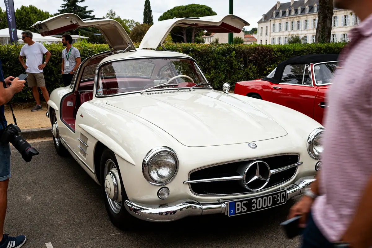 Voiture de collection 300SL Mercedes-Benz blanche avec portes ouvertes en papillon exposée dehors