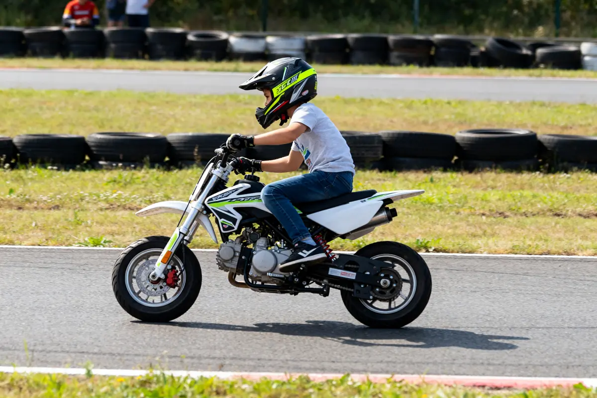 Enfant conduisant une petite moto poket bike sur circuit avec pneus de protection